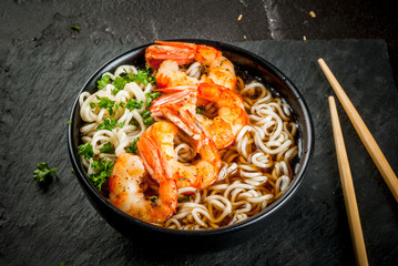 Asian soup with noodles (ramen), with miso paste, soy sauce, greens and shrimps prawn. On a black...