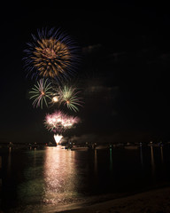 Fireworks explode over the river while boaters on the river enjoy a front row seat. 