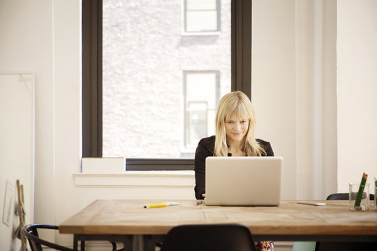 Young woman sitting at table and using laptop