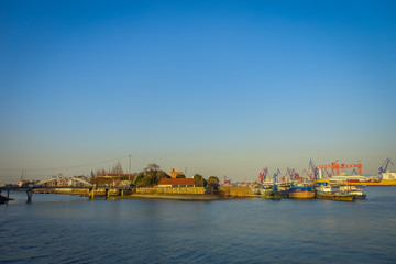 Fototapeta na wymiar SHANGHAI, CHINA: Shanghai riverbank, industrial boats and some port facilities lying waterfront, beautiful blue sky