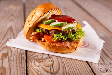 Delicious beef burgers with lettuce served on pieces of parchment paper on rustic wooden table
