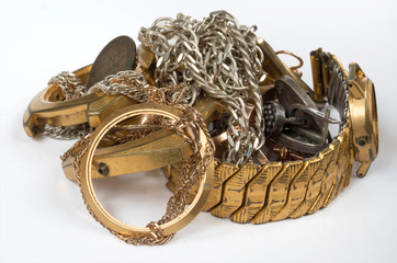 Scrap of precious metals. Old and broken jewelry, watches of gold and silver on a white background. Selective focus.