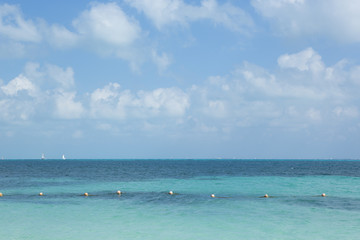 Turquoise water. An image of the Caribbean ocean. Sail boats on the background. Horizon.