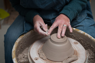 womans hands creating pottery objects in a ceramics workshop