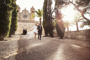 Fashionable wedding couple near Catholic church. Bride and Groom. Outdoor portrait