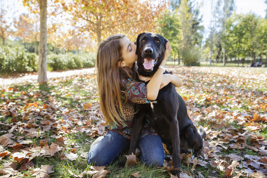 Girl kneeling and hugging dog in park