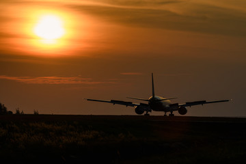 Naklejka na ściany i meble Airplane on runway in sunset