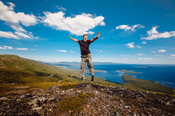 Obraz premium Male tourist man sitting jumping on a mountain on a white sea background. Kandalaksha, Murmansk region, the Kola Peninsula, Russia.