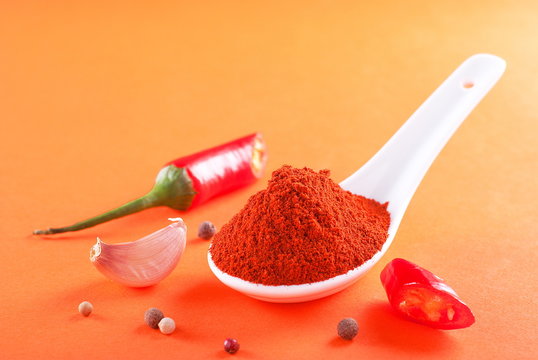 Ground red pepper in a white spoon on a fire background
