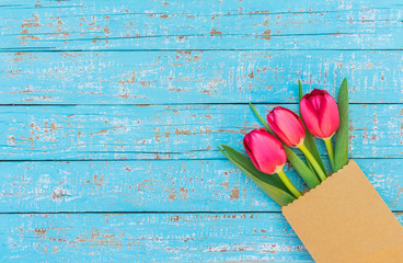 Fototapeta na wymiar Frische Tulpen Blumen in Geschenk Tüte auf Holz Hintergrund hellblau
