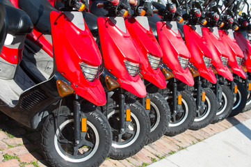 red scooters or motorcycles for sale or hire in row
