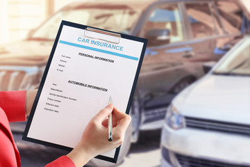 Woman filling in car insurance form on auto center background