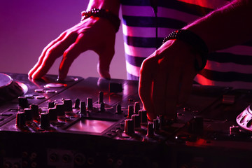 DJ mixing tracks on a mixer in a nightclub