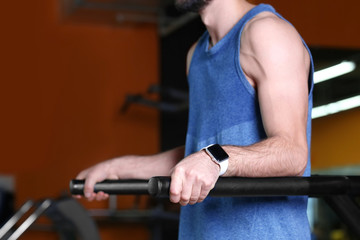 Young man with fitness tracker training in gym