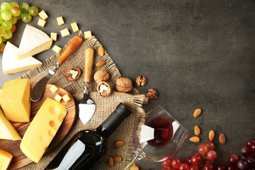 Composition of delicious cheese, grape, nuts and wine on grey table