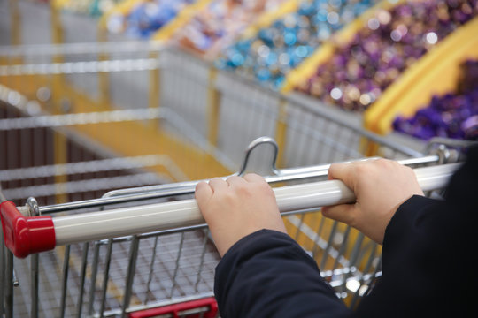 Female hands holding supermarket trolley