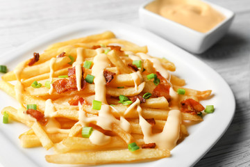 Plate with tasty cheese fries and sauce on white wooden table