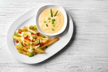 Plate with tasty cheese fries and sauce on white wooden table