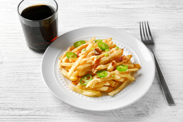 Plate with tasty cheese fries, sauce and glass of soda water on white wooden table