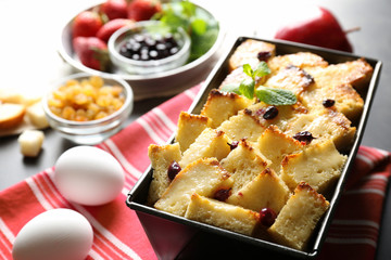 Delicious bread pudding with currant in baking dish on kitchen table