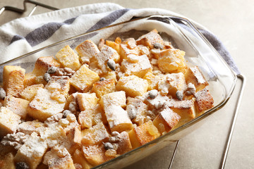 Bread pudding with raisins, walnuts and sugar powder in baking dish on table