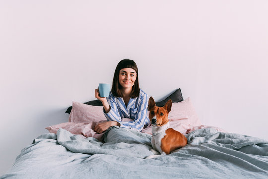 Hipster girl lounging in bed with coffee