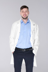 Young handsome pharmacist standing on grey background