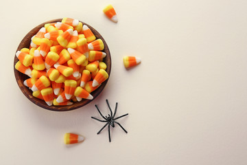Bowl with tasty Halloween candies on color background