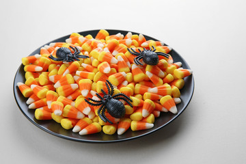 Plate with tasty Halloween candies on color background