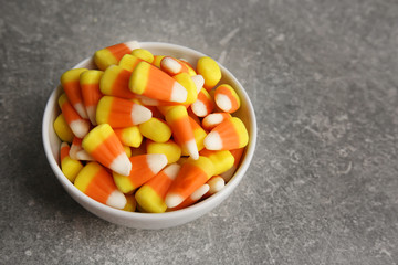 Bowl with tasty Halloween candies on light background