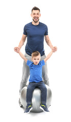 Fototapeta premium Handsome man and his son with fitball on white background