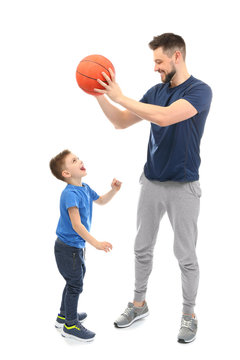 Handsome man and his son playing basketball on white background