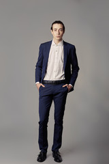 Business fashion man wearing blue suit with white shirt. Studio shot against grey