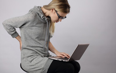 Bad posture effects.Female student using laptop and suffering from back pain