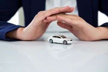 Businesswoman protecting toy car with hands