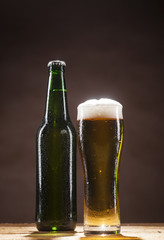 Beer bottle and mug on brown background