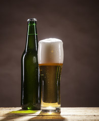 Beer bottle and mug on brown background