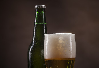 Beer bottle and mug on brown background
