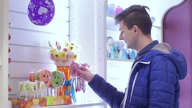 The young guy chooses a candy in the store