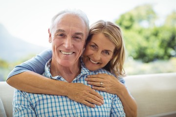 Portrait of smiling senior woman embracing a man in living room