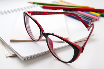 Red glasses on the notebook and colored pencils