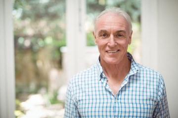 Portrait of smiling senior man standing in living room