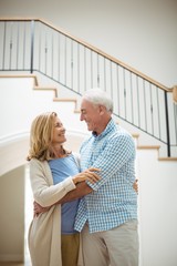 Senior couple embracing each other in living room