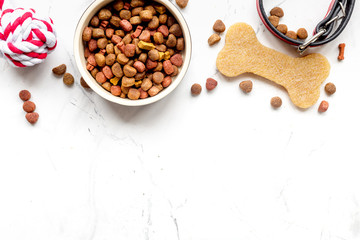 dry dog food in bowl on stone background top view