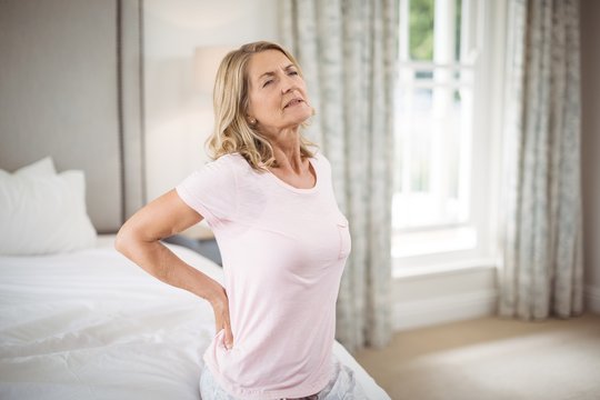 Senior woman having back pain in bedroom