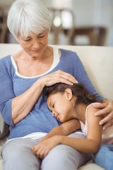 Obraz na płótnie Canvas Granddaughter sleeping on grandmothers lap in living room