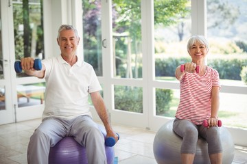 Senior couple exercising with dumbbells on exercise ball