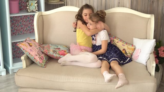 Little girl sister hugging sitting on the couch