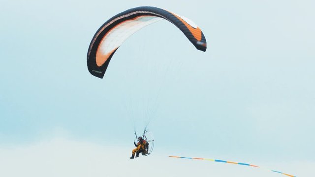 Paraglider flies over the land. Paragliding. Powered paraglide flying in the sky. Parachute