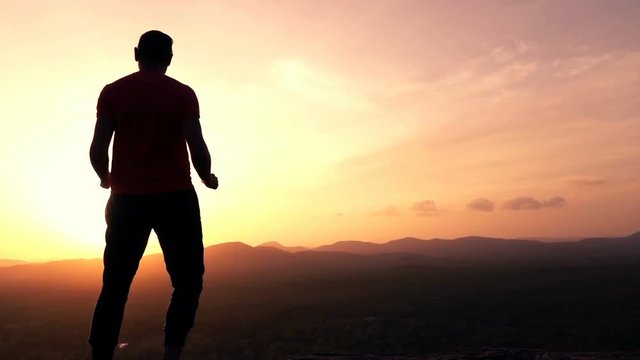 Happy man raising arms with victory on hill during sunset, super slow motion 240fps
